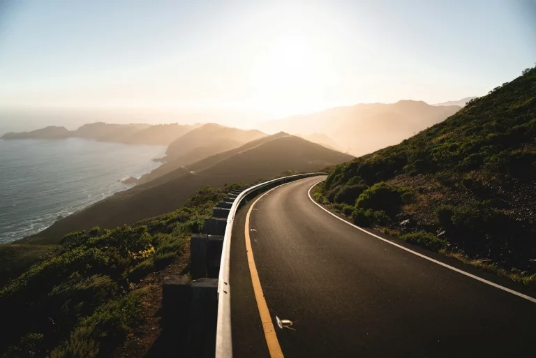 Perfectly smooth stretch of road with setting sun and the California coast to the left