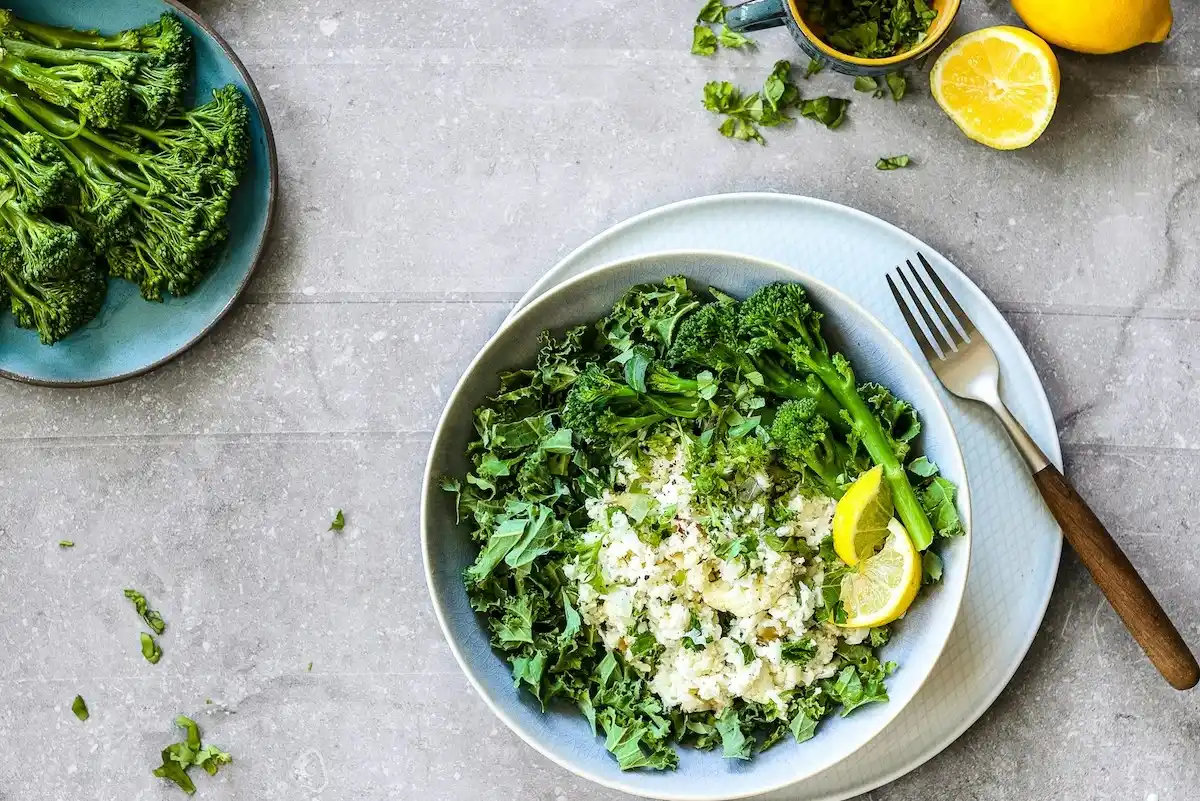 a white bowl filled with greens with a brown fork