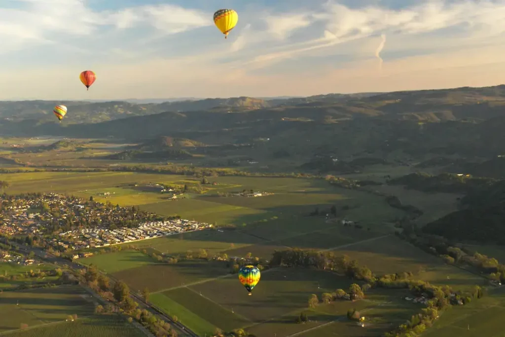 Napa valley floor surrounded by mountains with hot air balloons floating by