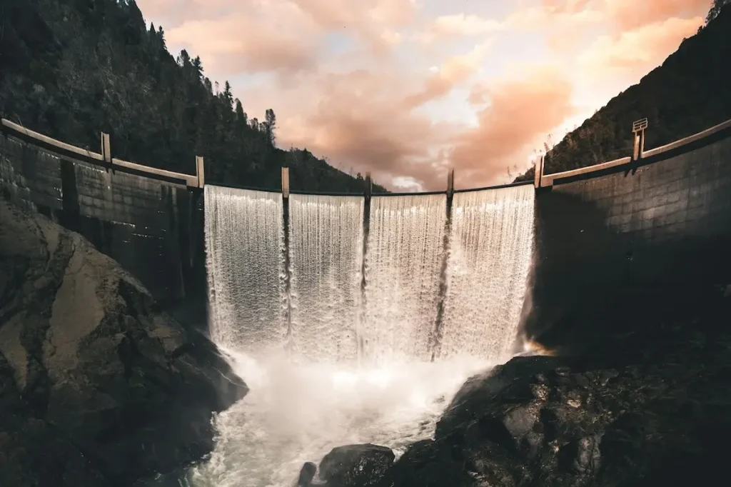 Horseshoe shaped dam with flowing water and pink clouds