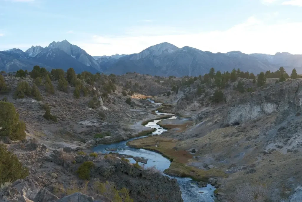 Winding lake through steep rocky cliffs with snow-capped mountains