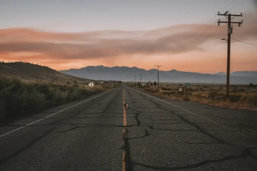 Battered road with fields and mountains at dusk